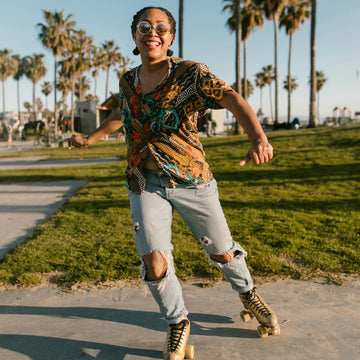 Joyful woman roller skating outdoors in ripped jeans and bold print – celebrating freedom, movement, and playful energy.