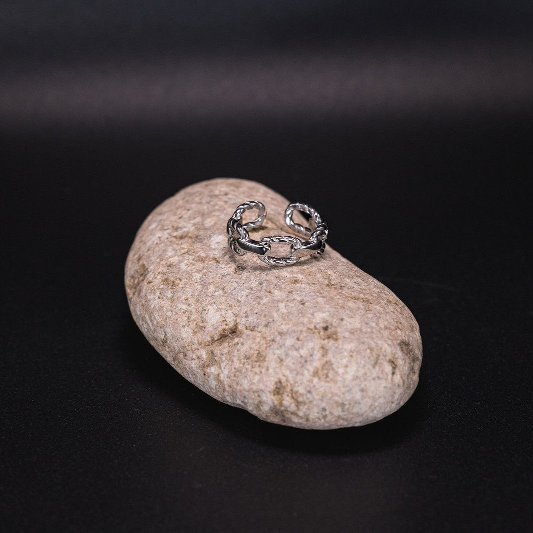 EQUØRA Anchor Link Ring — open-ended silver ring with interwoven link design, styled on a natural stone. A modern minimalist piece inspired by nautical textures and coastal energy.