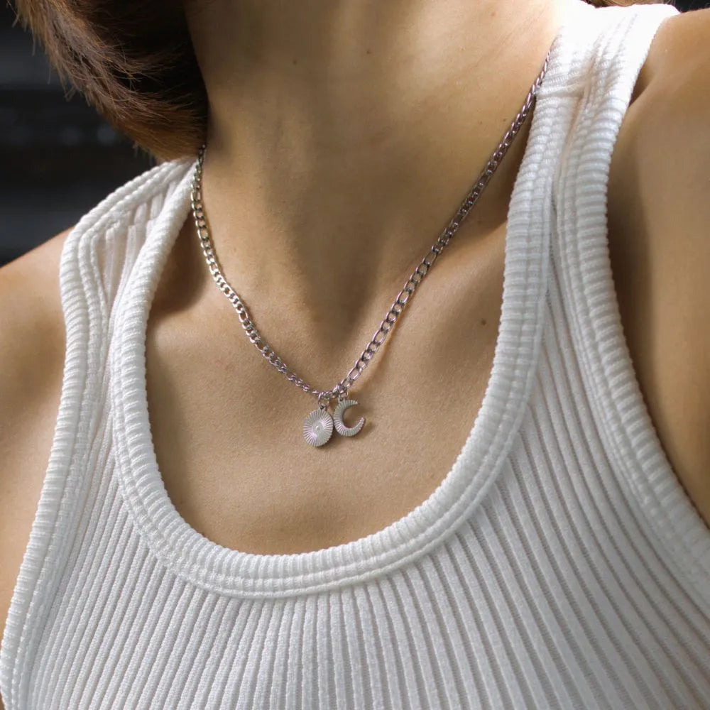 Silver crescent moon and sun pendant necklace worn on collarbone – capturing hope and duality.