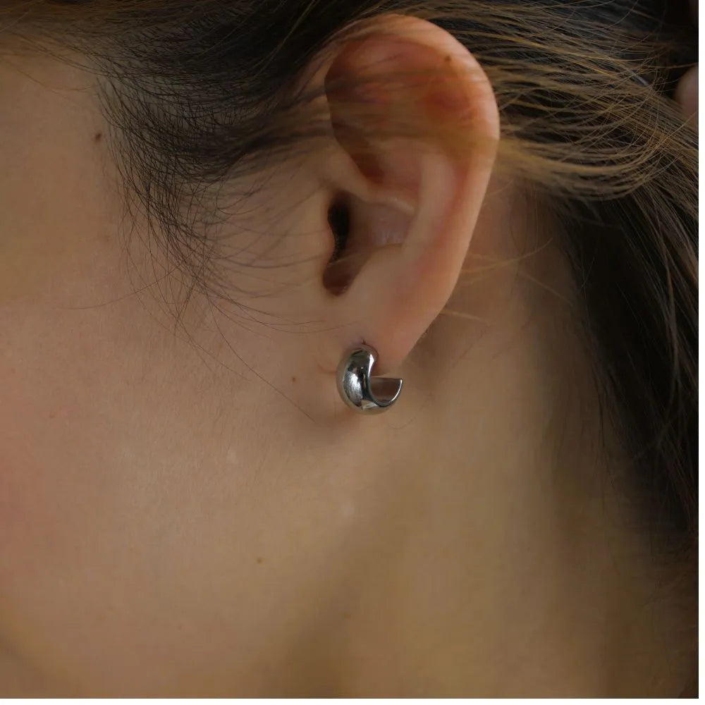 Curved silver stud earrings – a bold, minimal expression of presence and form.