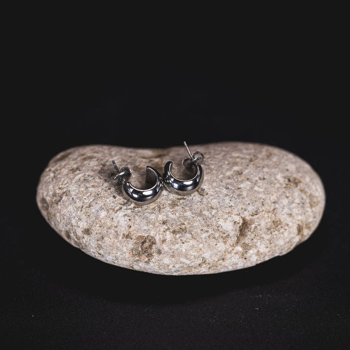 EQUØRA Echo Earrings — mini dome-shaped silver hoops with a high-polish finish, made from stainless steel and styled on a smooth stone. Water-friendly and built for everyday wear.