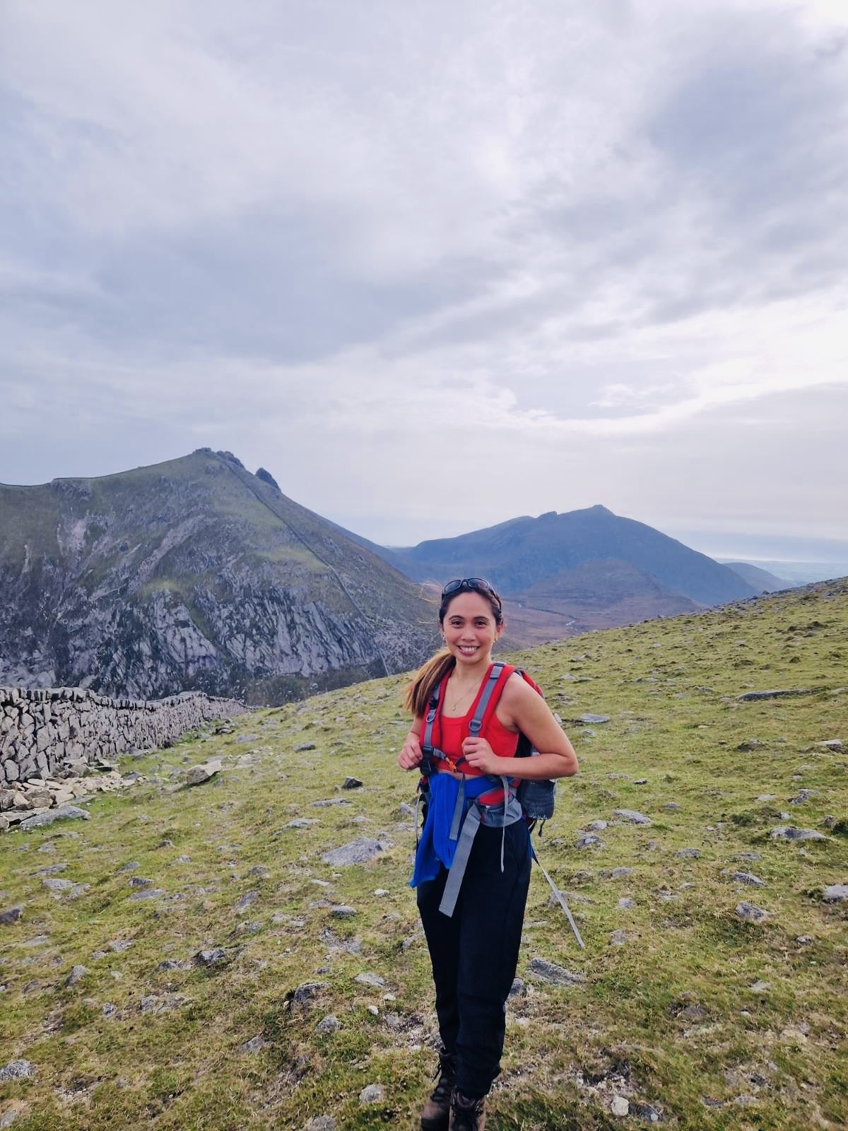 EQUØRA founder hiking in the mountains, wearing minimalist jewellery and a red top – reflecting strength, clarity, and the brand’s movement-ready ethos in nature.