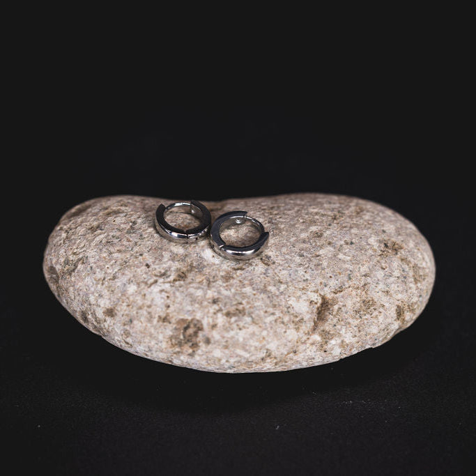 EQUØRA Halo Mini Earrings — minimalist stainless steel huggie hoops with a high-polish finish, styled on a smooth natural stone. Modern, water-resistant, and perfect for everyday wear.