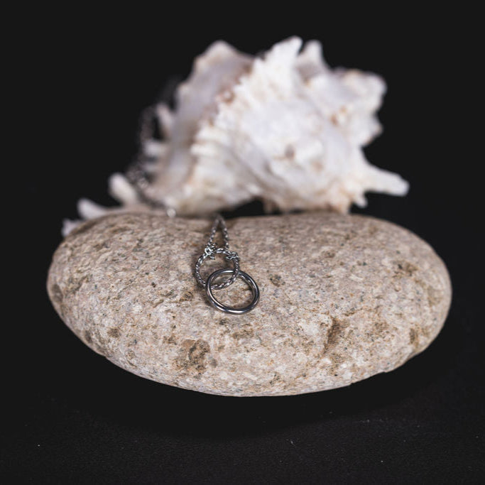 EQUØRA Infinity Bracelet — minimalist silver chain bracelet featuring interlocking infinity loops, symbolising eternal connection, elegantly presented on a natural stone background.