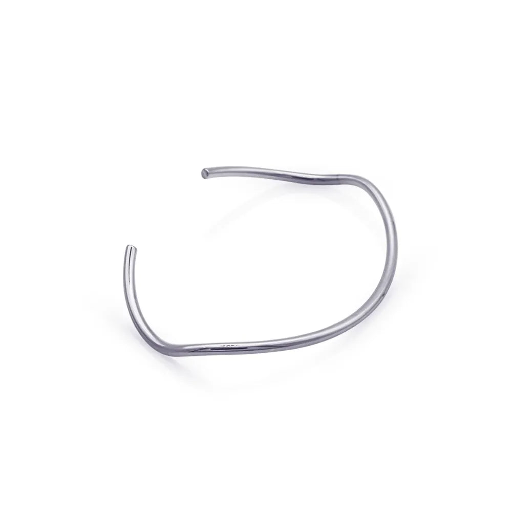 Curved silver Möbius bracelet laid flat – showcasing sculptural elegance inspired by infinite loops and inner balance.