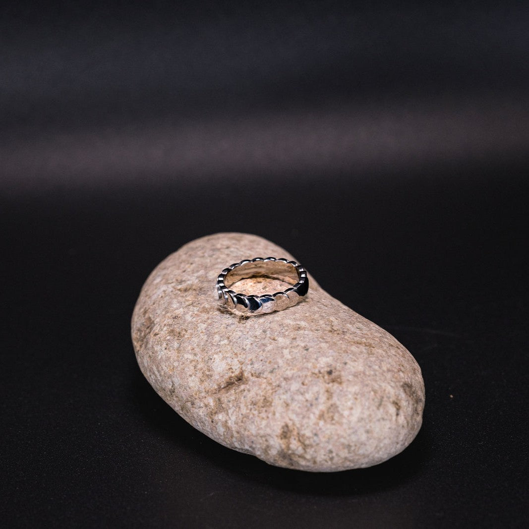 EQUØRA Waveform Ring — textured stainless steel ring with a wave-inspired edge design, displayed on a natural stone with a dark background. Bold and minimal statement jewellery.